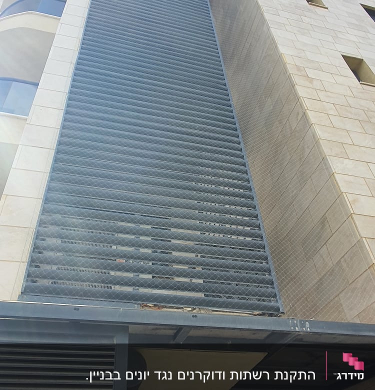 רשת מתכת על קיר בניין למניעת כניסת יונים